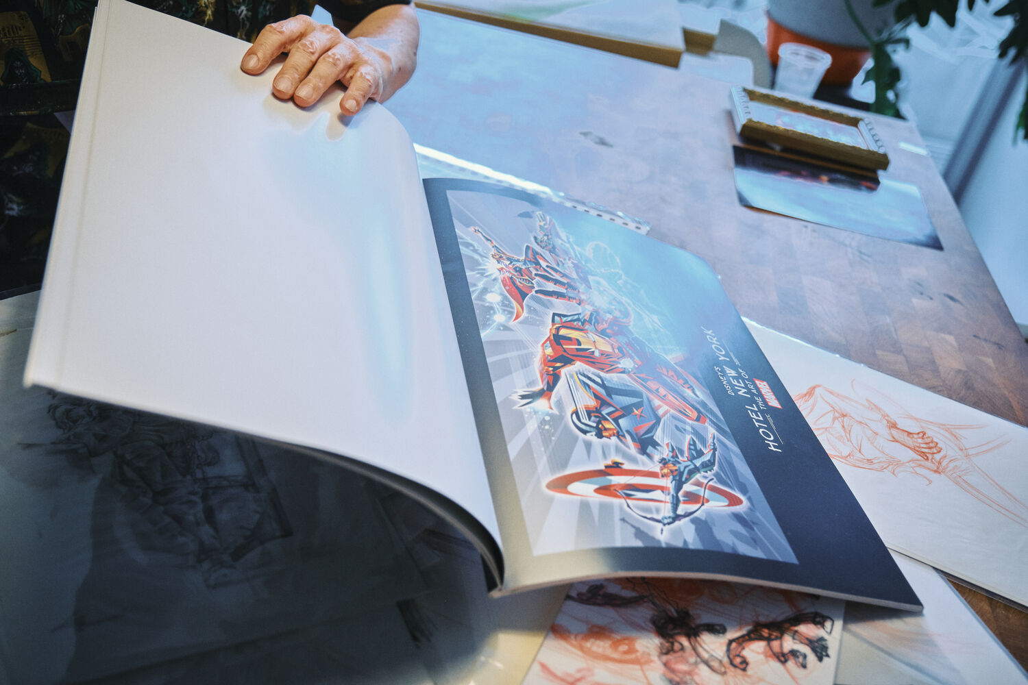 作品集を開き、手がけたアートワークを見せる手元